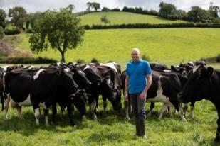 Milk supplier Alan Clarke standing in a field of cattle.