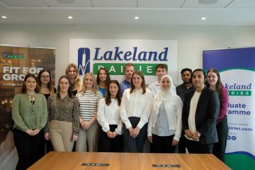 A group of graduates standing and smiling in an office.