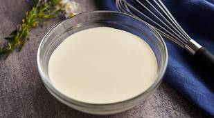 A bowl of Lakeland Dairies Whipping Cream with a whisk next to it