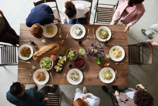 Dining table full of food with six people dining and socialising