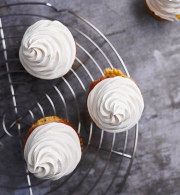 Image of cupcakes on a display stand with whipped cream piped on the top, made using Lakeland Dairies products