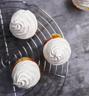 Image of cupcakes on a display stand with whipped cream piped on the top, made using Lakeland Dairies products
