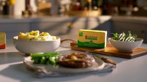 Packet of Lakeland Dairies butter being placed onto a steak with green beans