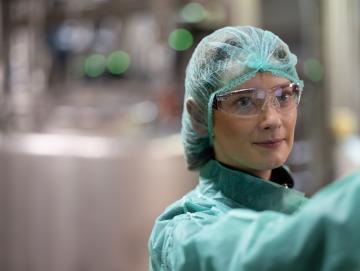 A woman wearing light blue PPE and safety goggles.