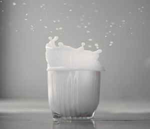 Glass of milk with milk splashed above