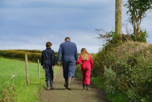 A farmer and his two children walking on their farm.