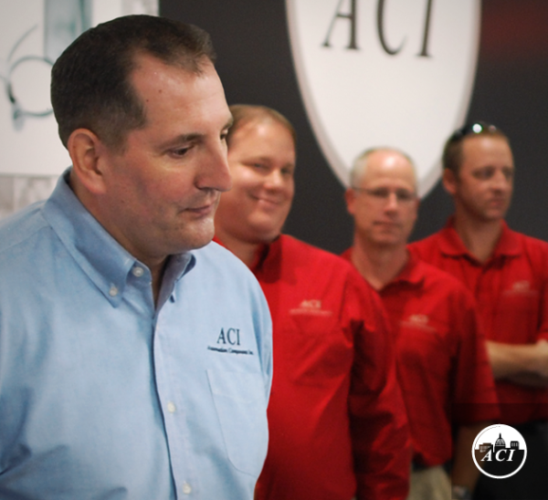 ACI employee in blue shirt with other employees behind him